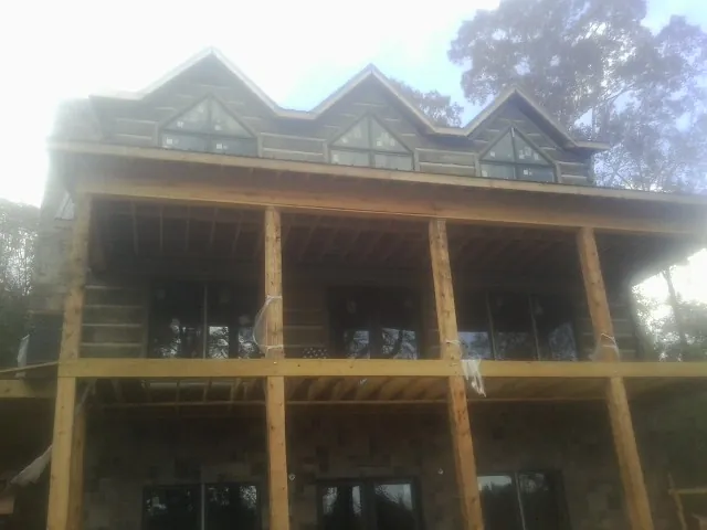Dormers and porch framing on a large log home under construction — Roof Coating work by our crew in Lafferty