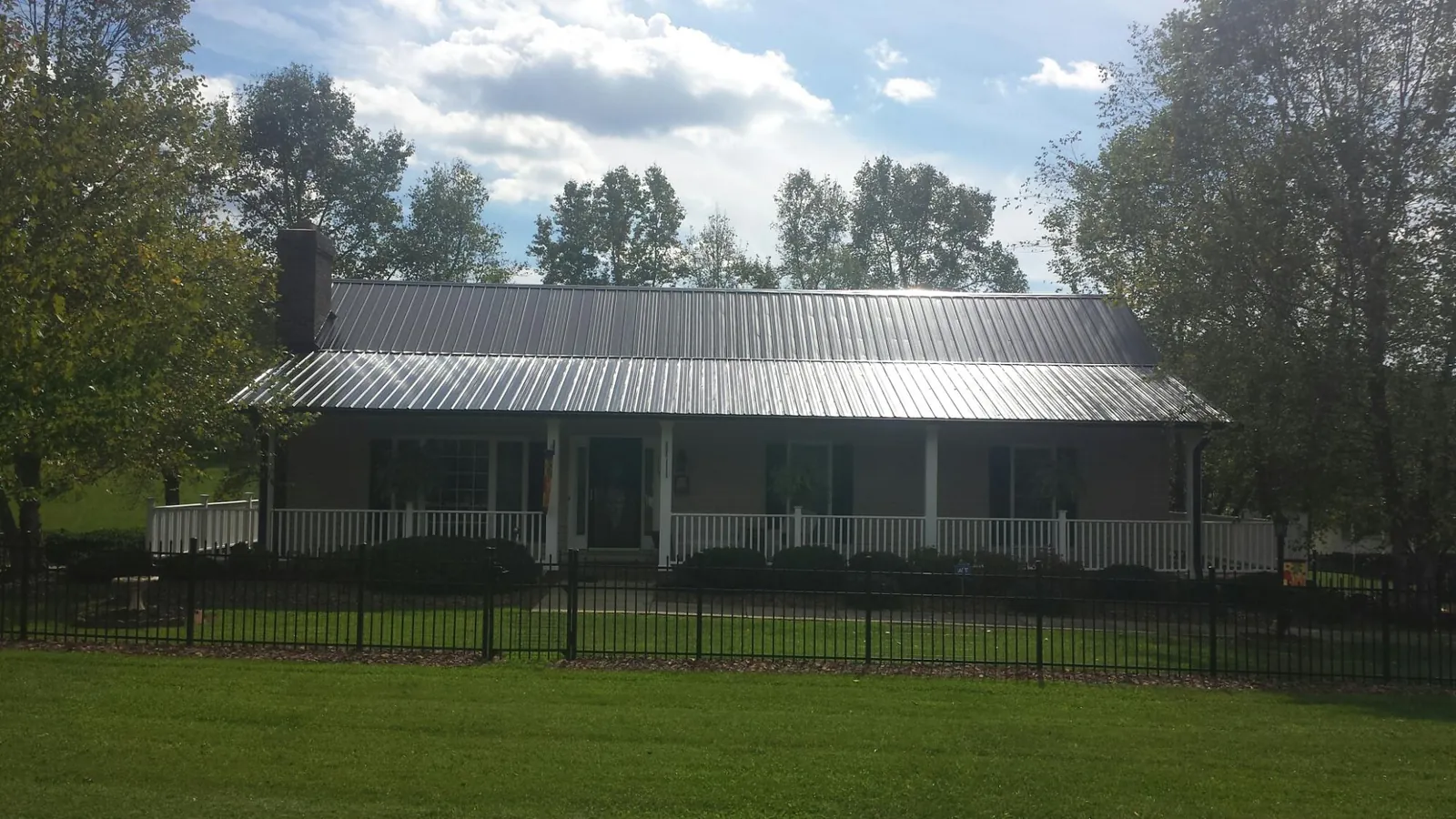 Gray metal roof on a brick ranch with a full width front porch — Gutter Guard Installation work by our crew in Lafferty
